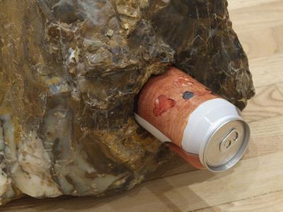 A detail shot of an orange and white labeled can of beer snuggly fit into a piece of polka-dot agate.