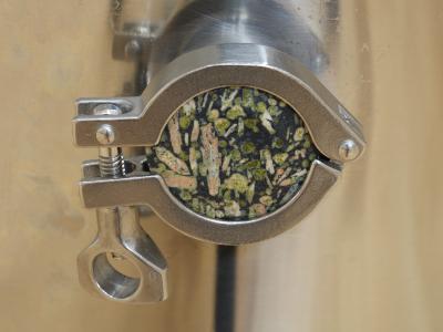 A detail shot of a customized flowerstone with epidote tri-clover cap on a stainless steel brewing kettle.