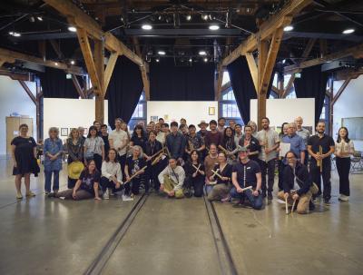 Participants pose in impromptu rows for a group photo. Many of them hold their instruments in hand. 
