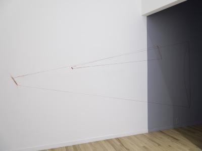 A red drawing on a white and blue wall of a small conical shape nestled inside a large conical shape. They resemble two megaphones. 