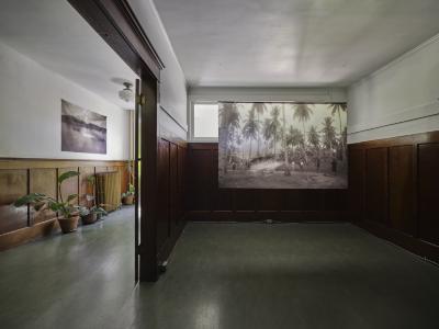 Two sepia photographs printed on sheer textiles are on display on the second floor of Western Front. One is attached to the wall at the top of the stairs, while the other is suspended from a dowel in the Grand Luxe Hall vestibule.