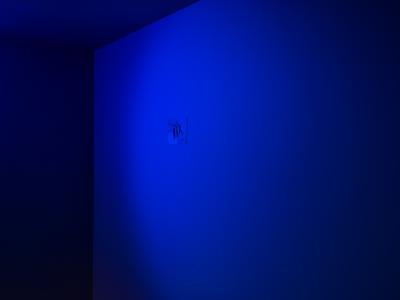 A small image featuring three figures dangling from a pole is attached to a blue wall.
