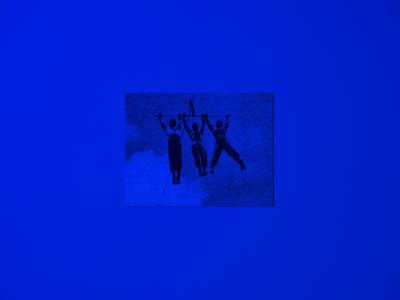 A postcard sized image of three figures hanging from a pole, affixed on a blue wall. 