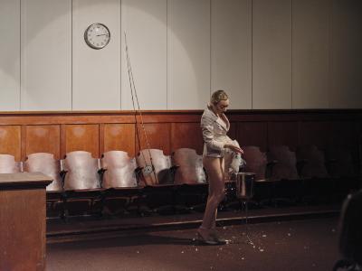 Marie Segolene Brault pours out a bag of ice into a metal bucket and onto the carpeted floor. A fishing rod rests against a wall behind her.