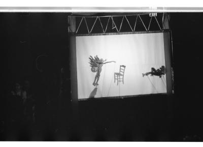 A portable shadow theatre depicts two shadow puppet figures and a shadow puppet chair.