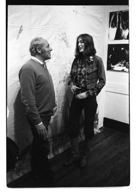 Henry Greenhow and Monica Holden-Lawrence stand in front of a wall splattered with fluids. 