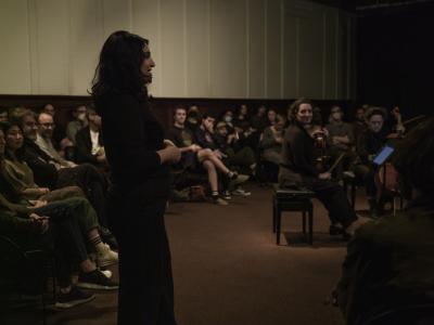 Sarah Davachi addresses the crowd, who are sitting in the round in the Grand Luxe Hall, as Stéphanie and Isabelle Bozzini look on while holding their viola and cello.